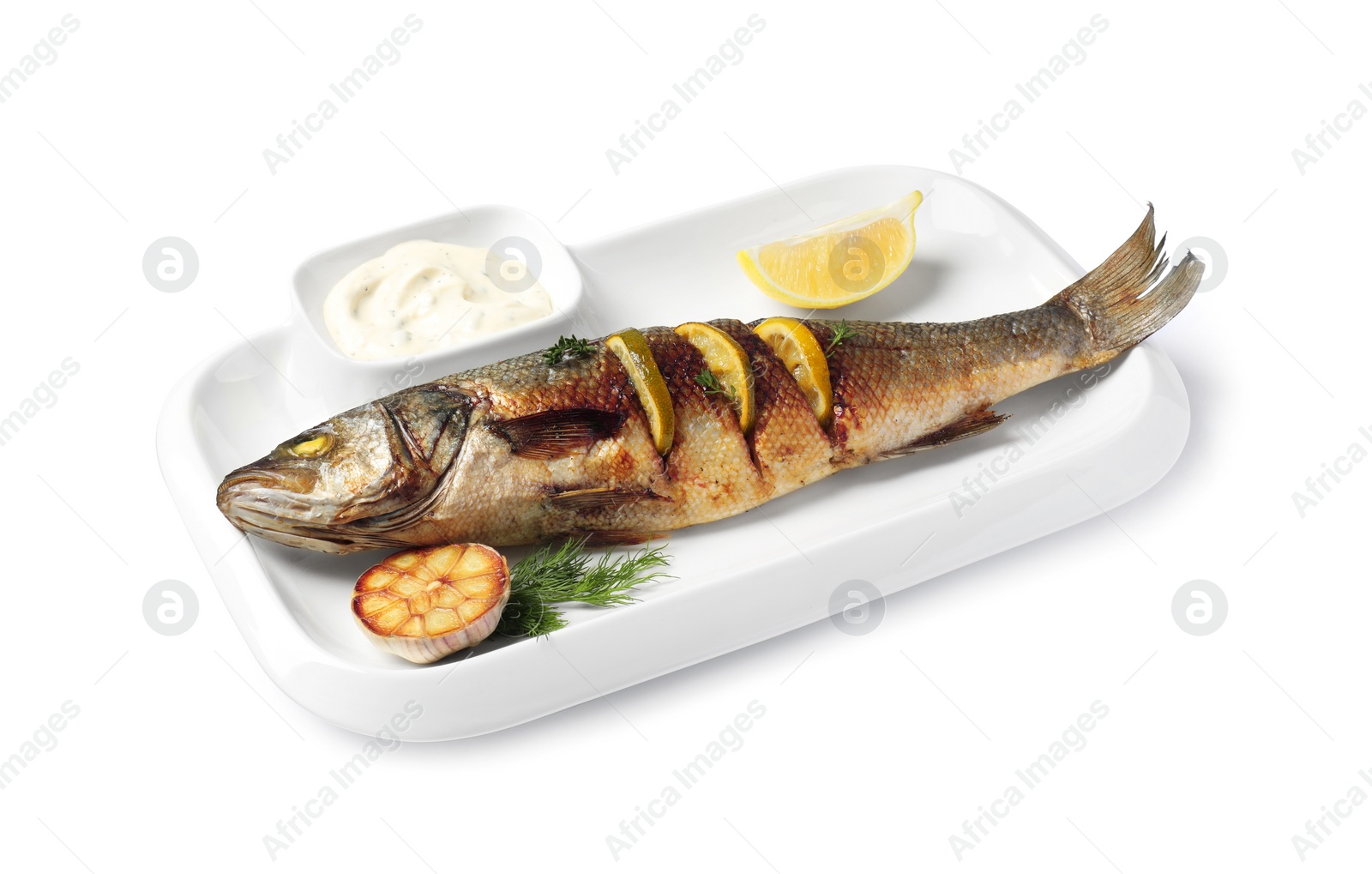 Photo of Plate with delicious roasted sea bass fish, garlic, slice of lemon and sauce on white background