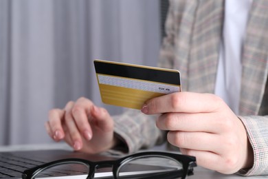 Online payment. Woman with laptop and credit card at white marble table, closeup