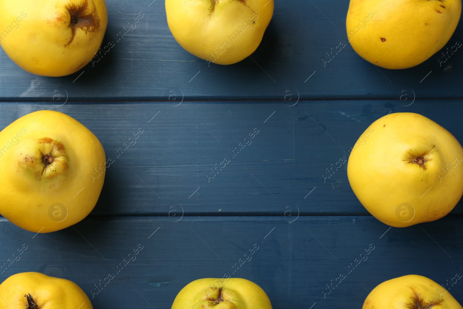 Photo of Tasty ripe quinces on blue wooden table, flat lay. Space for text