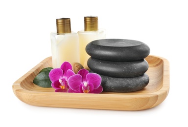 Photo of Wooden tray with spa stones, orchid flowers and bottles on white background