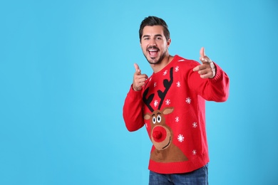 Photo of Portrait of happy young man in Christmas sweater on light blue background