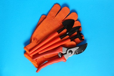 Photo of Gardening gloves and tools on light blue background, flat lay