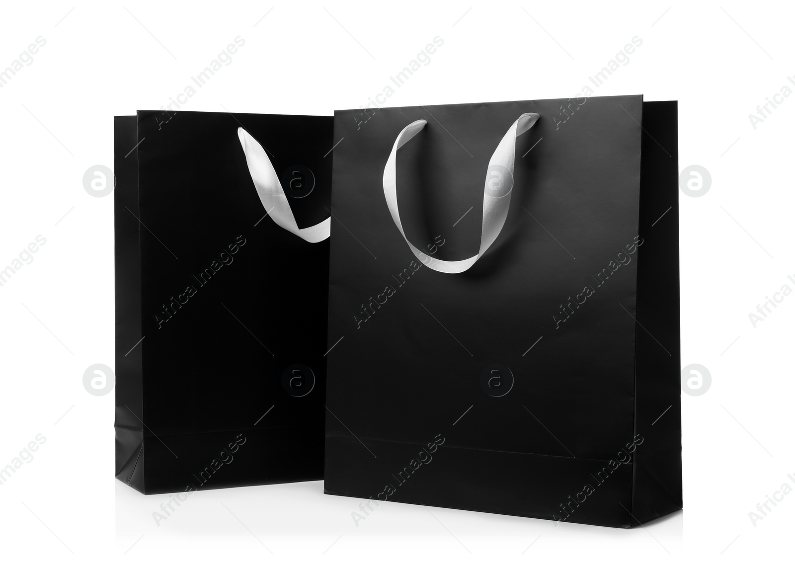 Photo of Paper shopping bags with ribbon handles on white background. Mockup for design