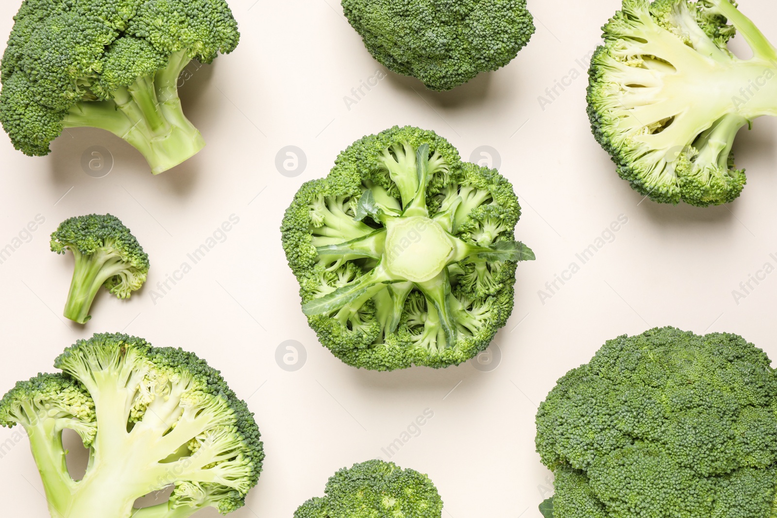 Photo of Fresh tasty broccoli on light beige background, flat lay