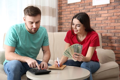 Beautiful young couple with money at home