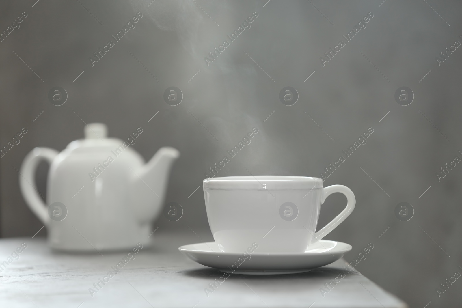 Photo of Cup of tea and saucer on table against gray background