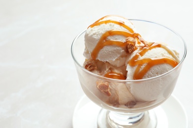 Photo of Bowl with caramel ice cream on light background