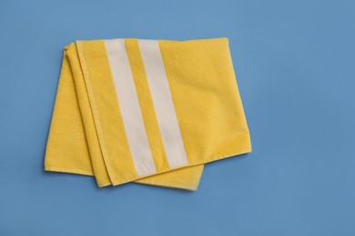 Photo of Folded yellow beach towel on blue background, top view