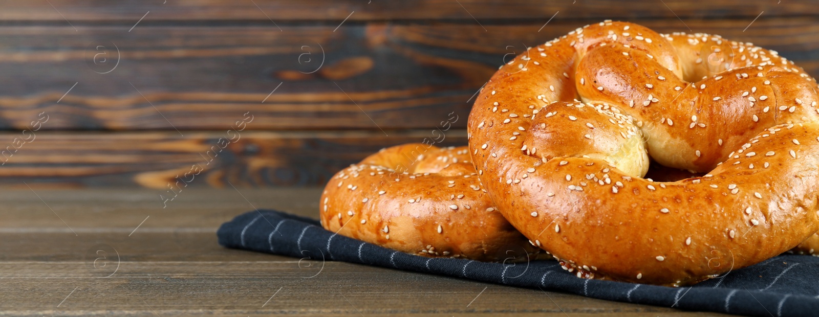 Image of Tasty freshly baked pretzels on wooden table, space for text. Banner design