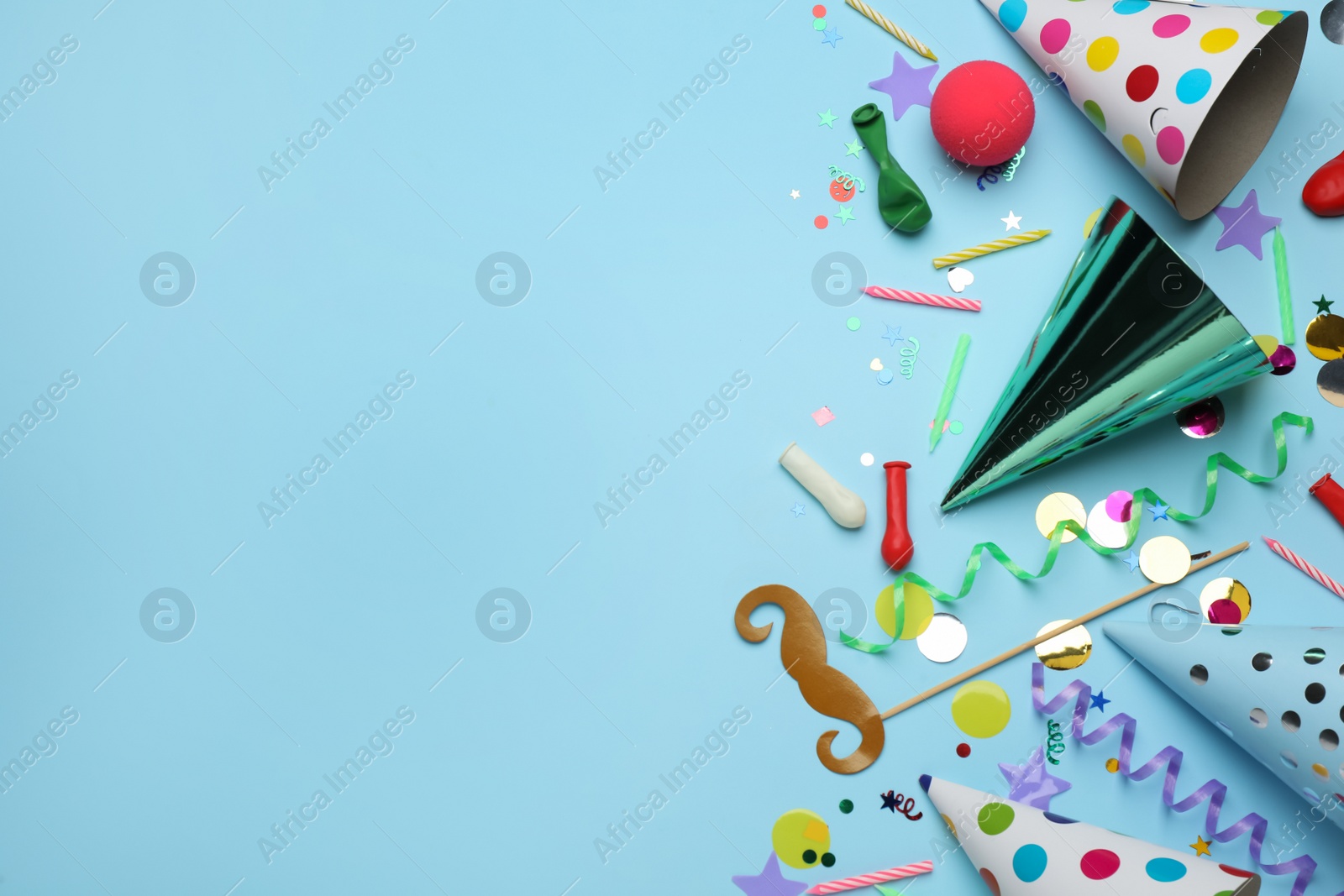 Photo of Flat lay composition with party hats and other festive items on light blue background, space for text. Birthday surprise
