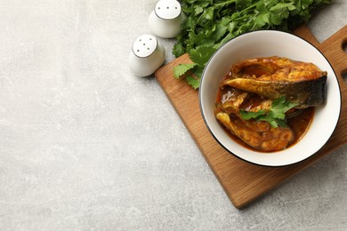 Photo of Tasty fish curry served on light grey table, flat lay. Space for text. Indian cuisine