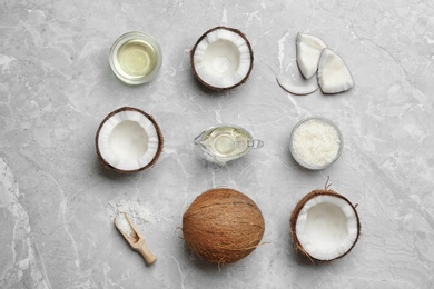 Photo of Glassware with natural organic oil and coconuts on grey stone background, flat lay