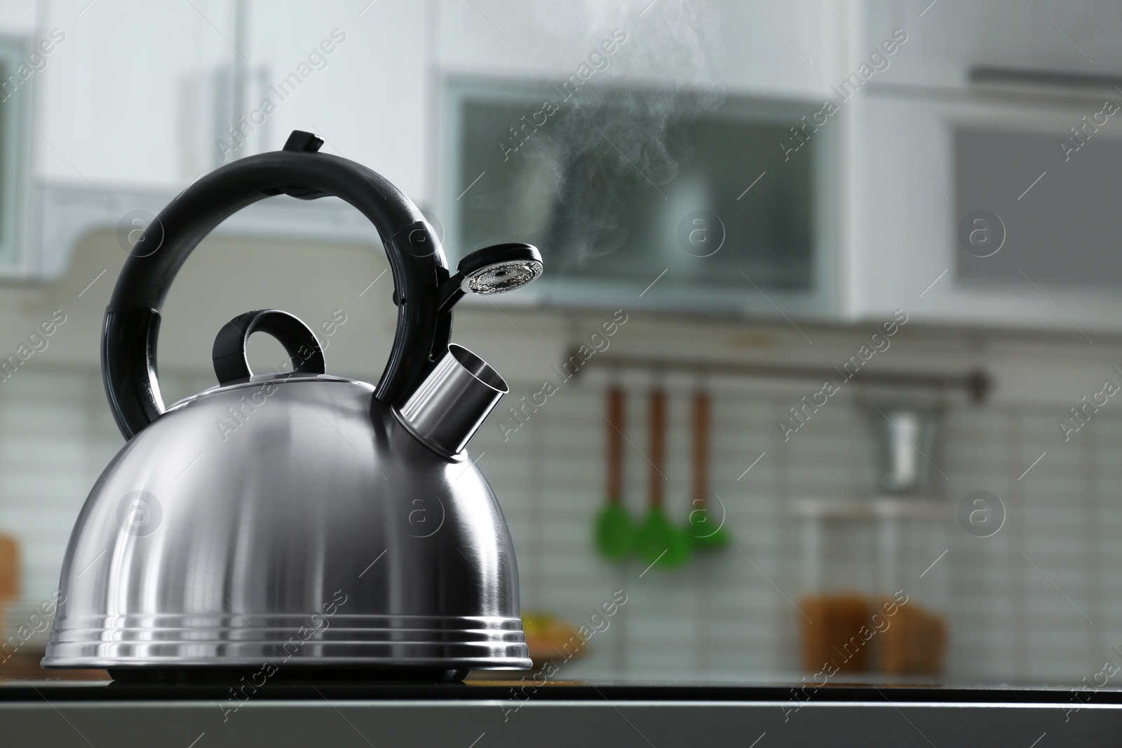 Photo of Modern kettle with whistle on stove in kitchen, space for text