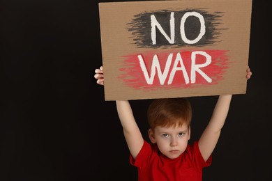 Photo of Boy holding poster No War against black background, space for text