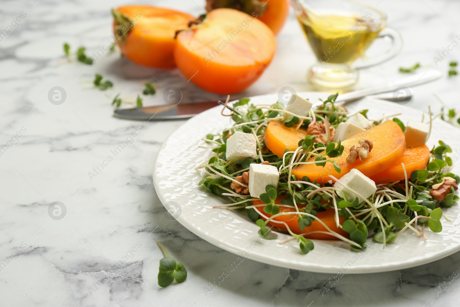 Photo of Delicious persimmon salad served on white marble table, closeup