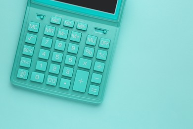 Turquoise calculator on light blue background, top view. Space for text