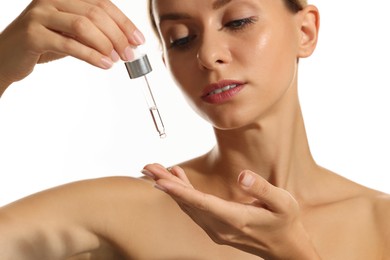 Beautiful woman applying cosmetic serum onto her hand on white background