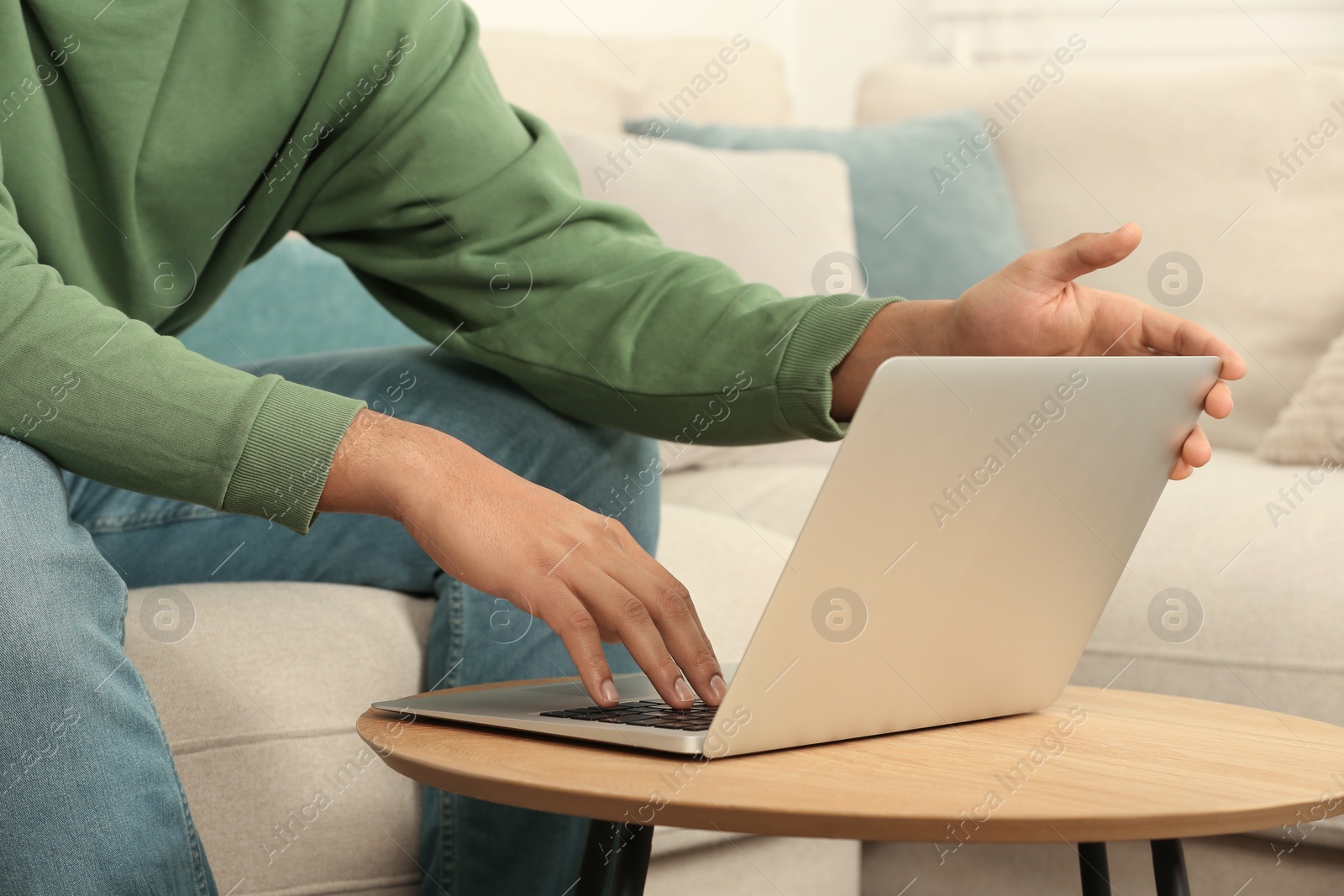 Photo of African American man working on laptop at table indoors, closeup