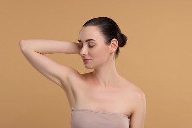 Beautiful woman showing armpit with smooth clean skin on beige background