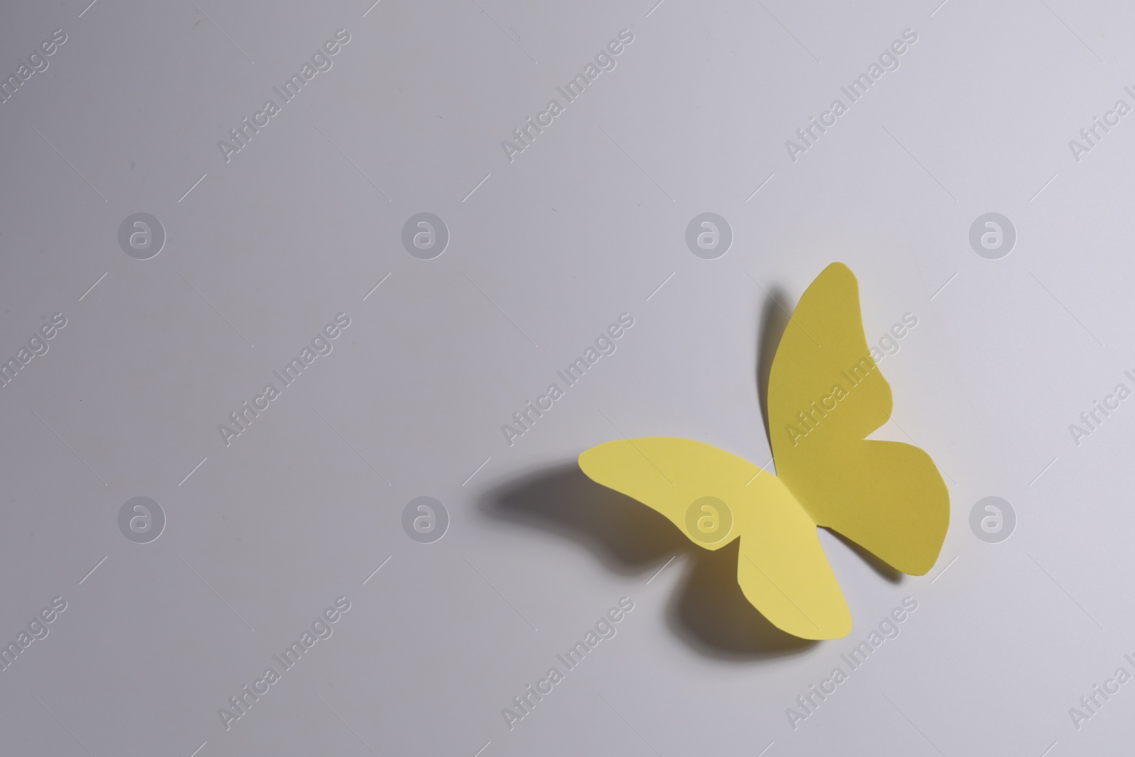 Photo of Yellow paper butterfly on light background, top view. Space for text