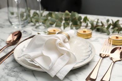 Photo of Beautiful place setting with candles and eucalyptus on white marble table