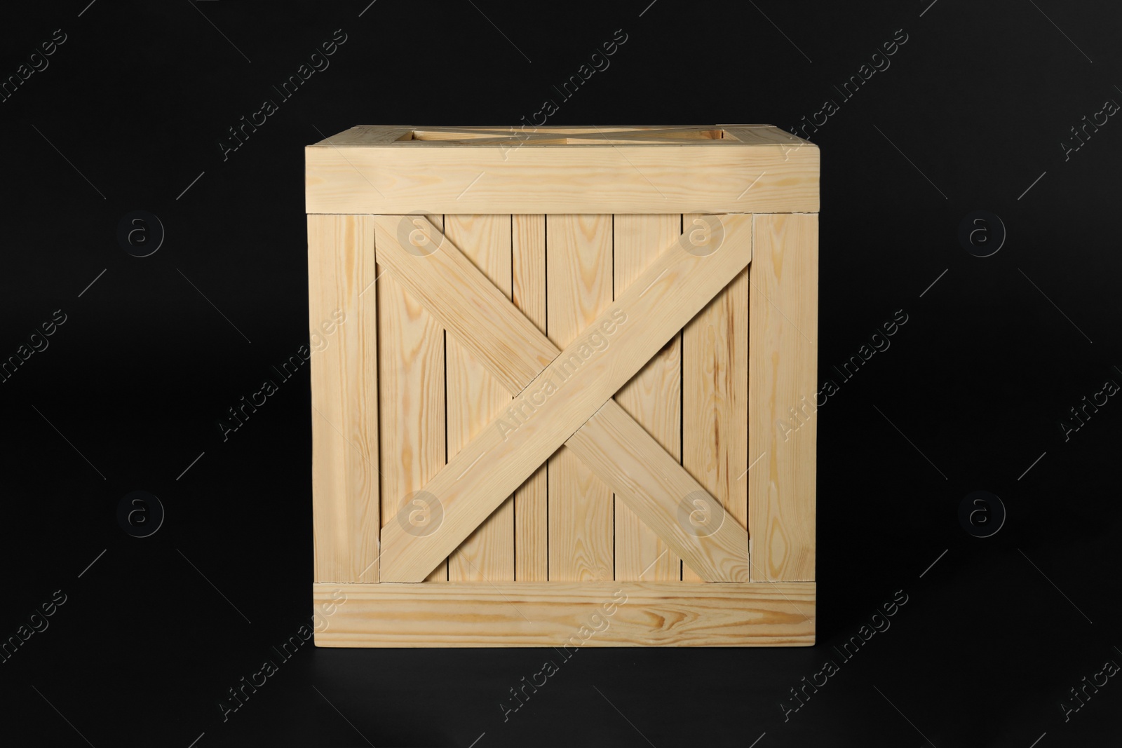 Photo of Closed wooden crate on black background. Shipping container