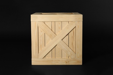 Photo of Closed wooden crate on black background. Shipping container