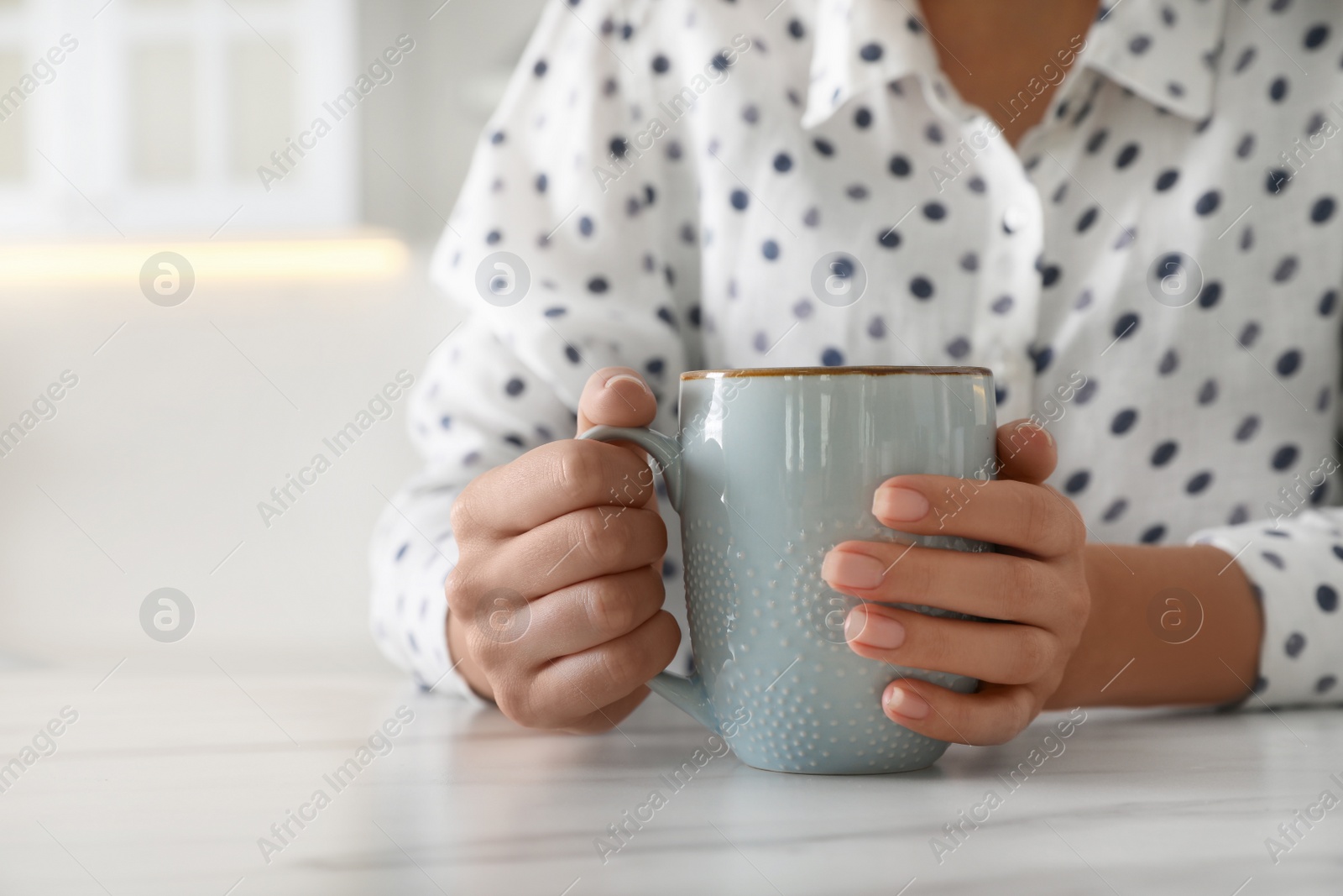 Photo of Woman with blue cup at table indoors, closeup