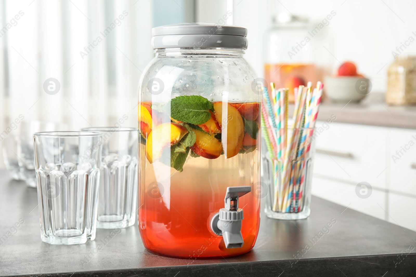 Photo of Peach cocktail in jar with tap on table. Refreshing drink