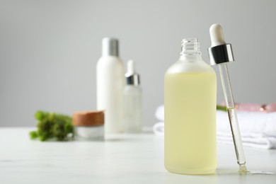 Photo of Bottle of hydrophilic oil and pipette on white table, space for text