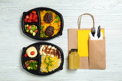 Photo of Flat lay composition with lunchboxes on white wooden table. Healthy food delivery