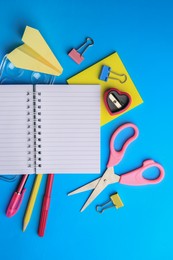 Flat lay composition with blank notebook and other school stationery on light blue background, space for text. Back to school