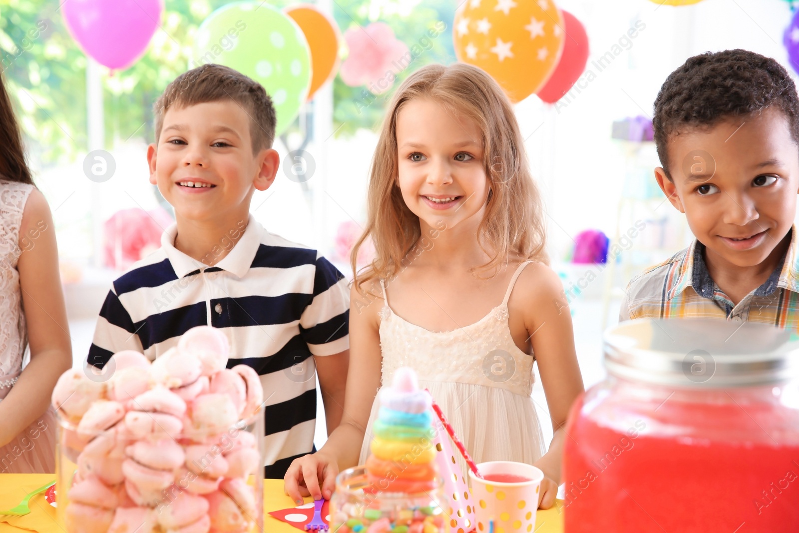 Photo of Cute children near table with treats at birthday party indoors