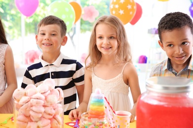 Photo of Cute children near table with treats at birthday party indoors