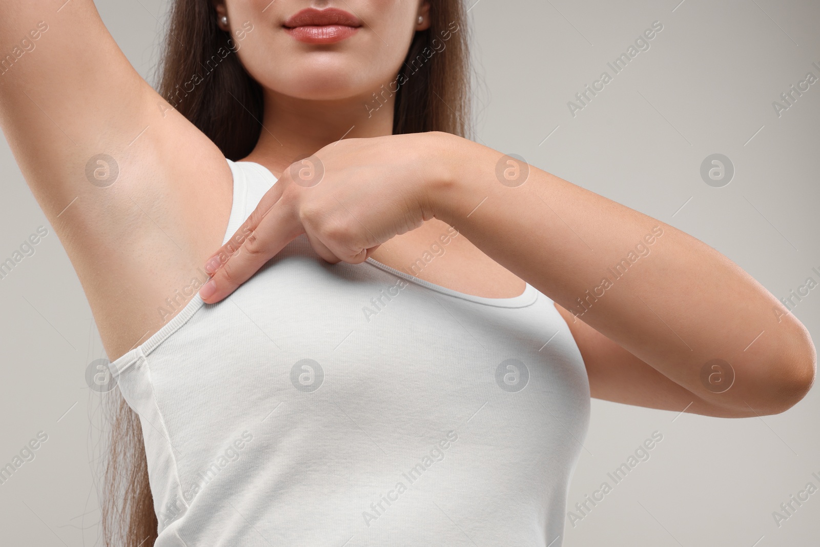 Photo of Woman doing breast self-examination on light grey background, closeup