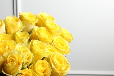 Beautiful bouquet of yellow roses near white wall, closeup. Space for text