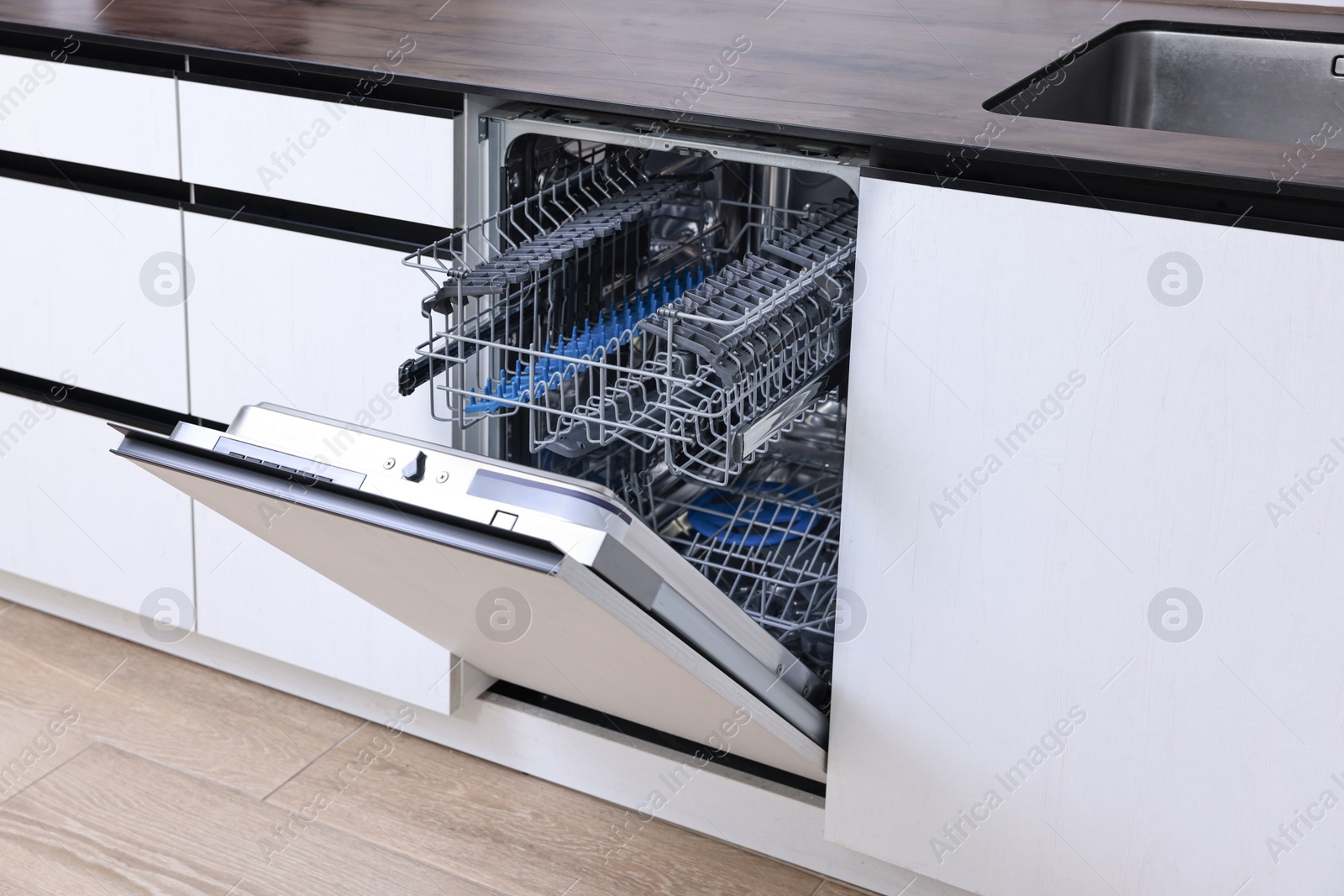 Photo of Built-in dishwasher with open door indoors. Home appliance