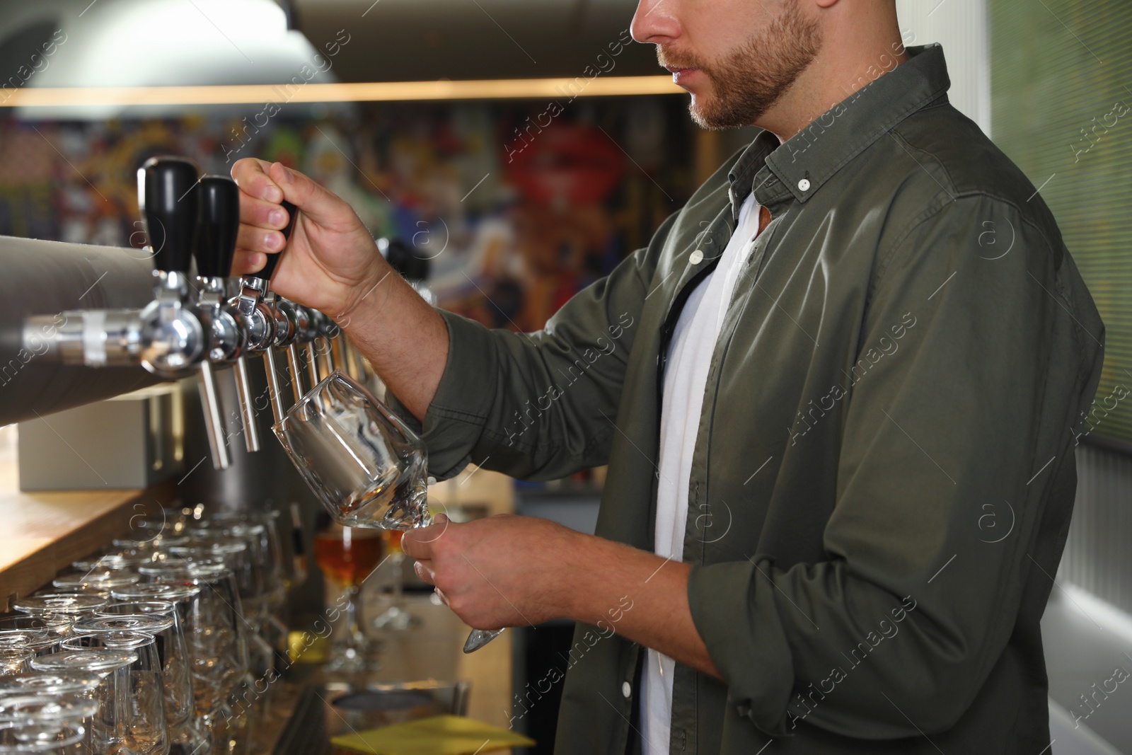 Photo of Bartender pouring fresh beer into glass in pub, closeup