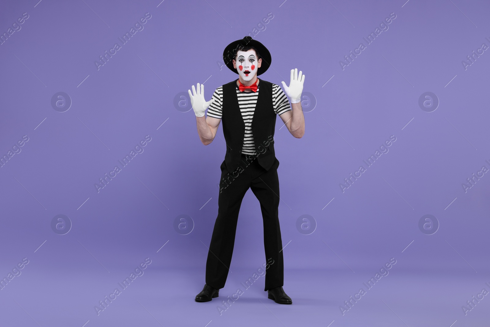 Photo of Mime artist making shocked face on purple background