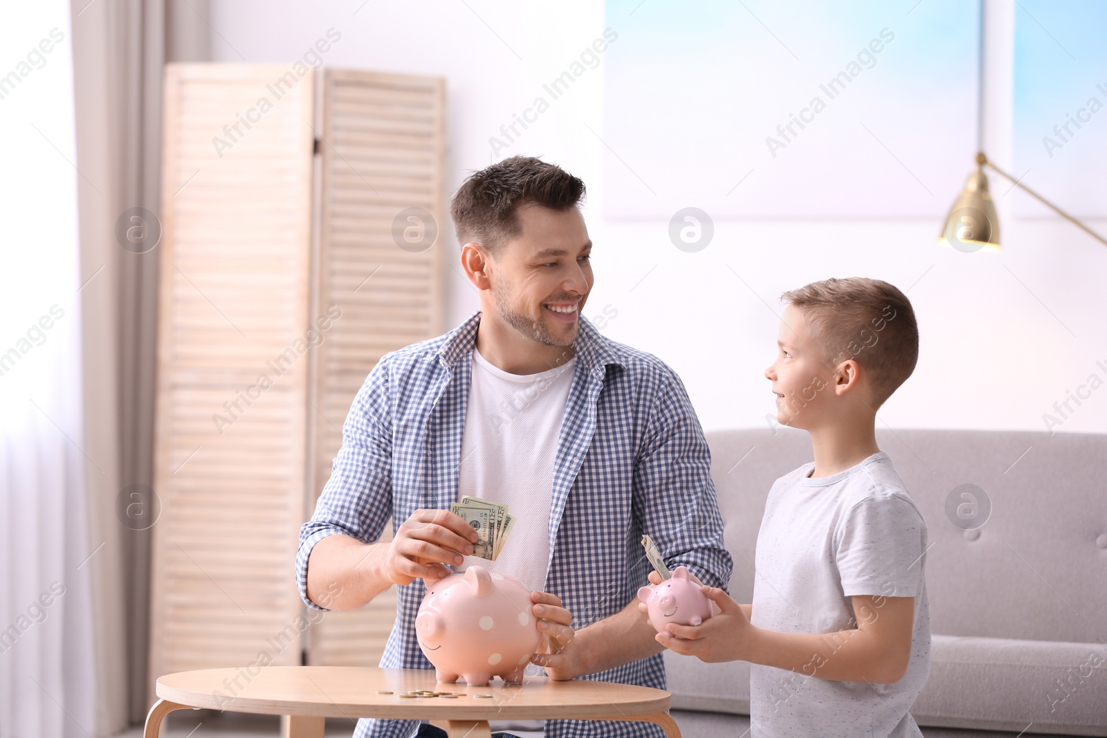 Photo of Family with piggy banks and money at home