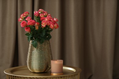 Photo of Bouquet of beautiful roses and burning candle on table indoors, space for text. Interior elements