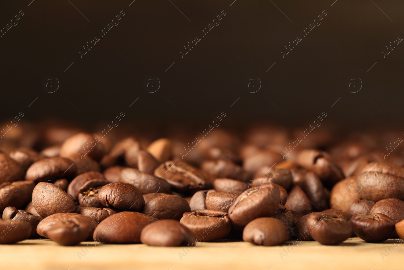 Photo of Many roasted coffee beans on wooden table, closeup