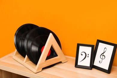 Photo of Vinyl records and pictures on wooden table near orange wall