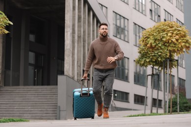 Photo of Being late. Worried man with suitcase running outdoors