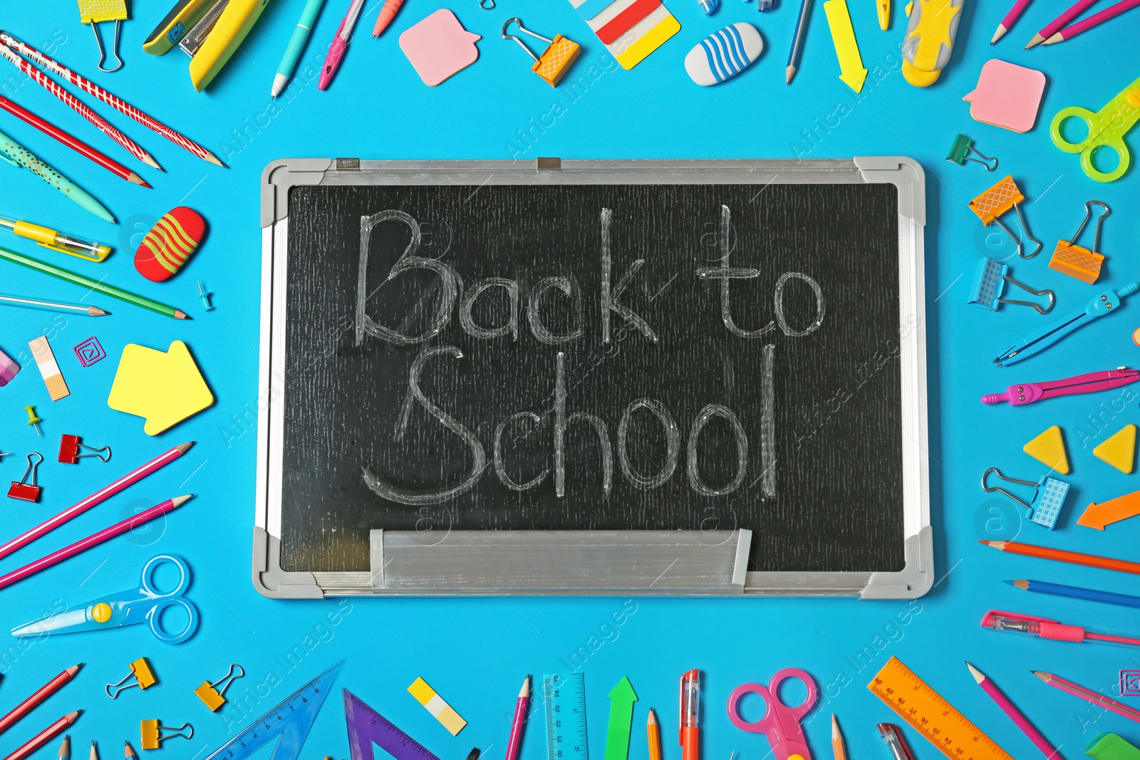 Photo of Flat lay composition with different school stationery and small chalkboard on color background