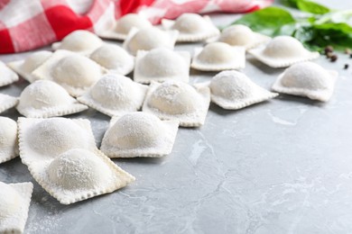 Photo of Uncooked ravioli on grey marble table, closeup. Space for text
