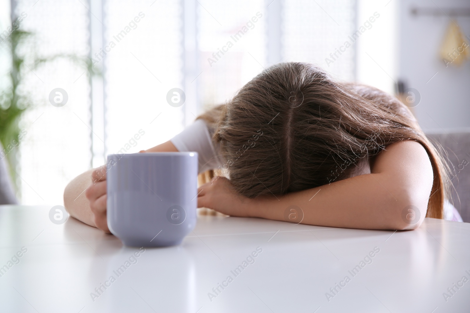 Photo of Young woman with cup of drink sleeping at home in morning