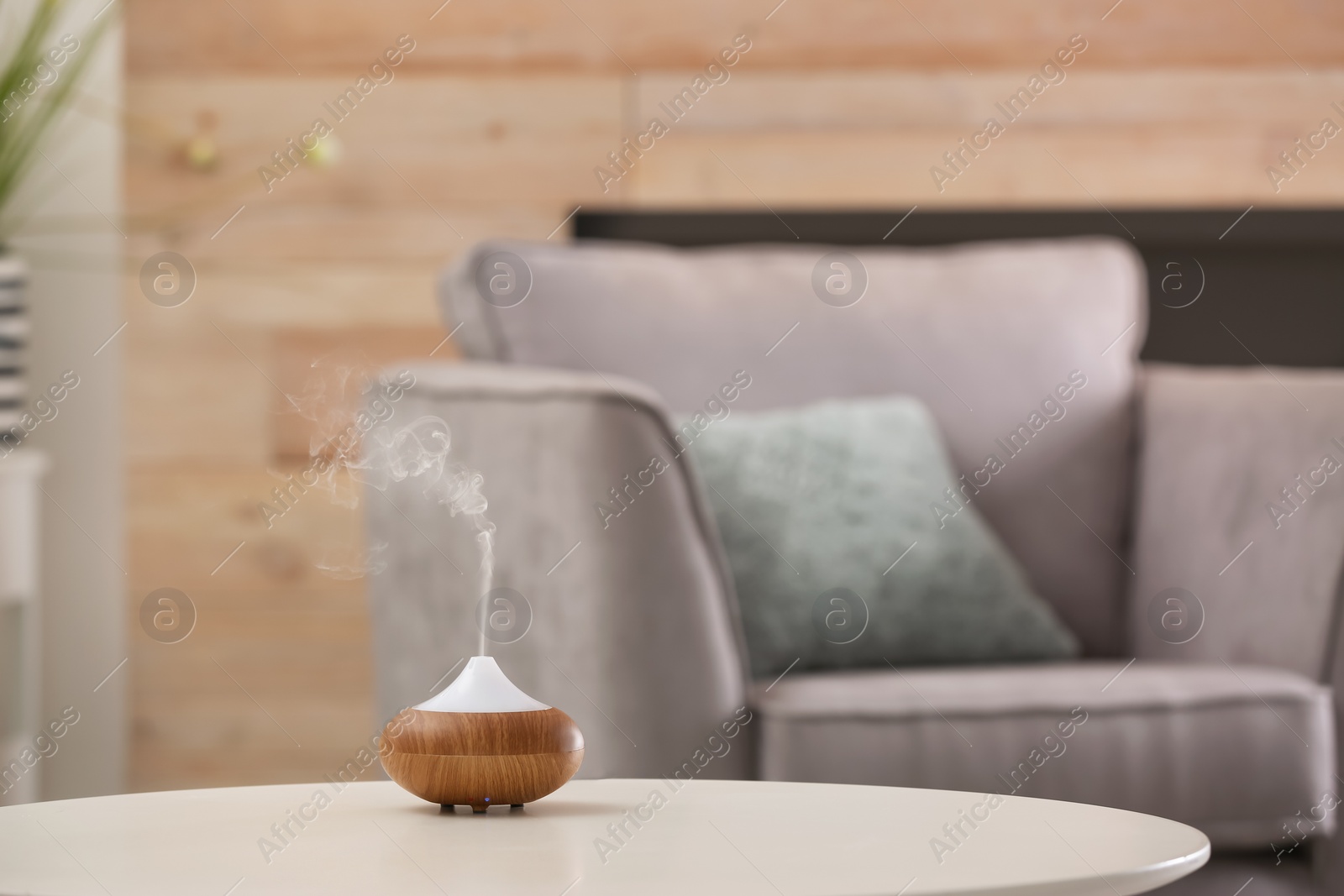 Photo of Aroma oil diffuser lamp on table against blurred background