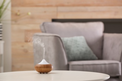 Aroma oil diffuser lamp on table against blurred background