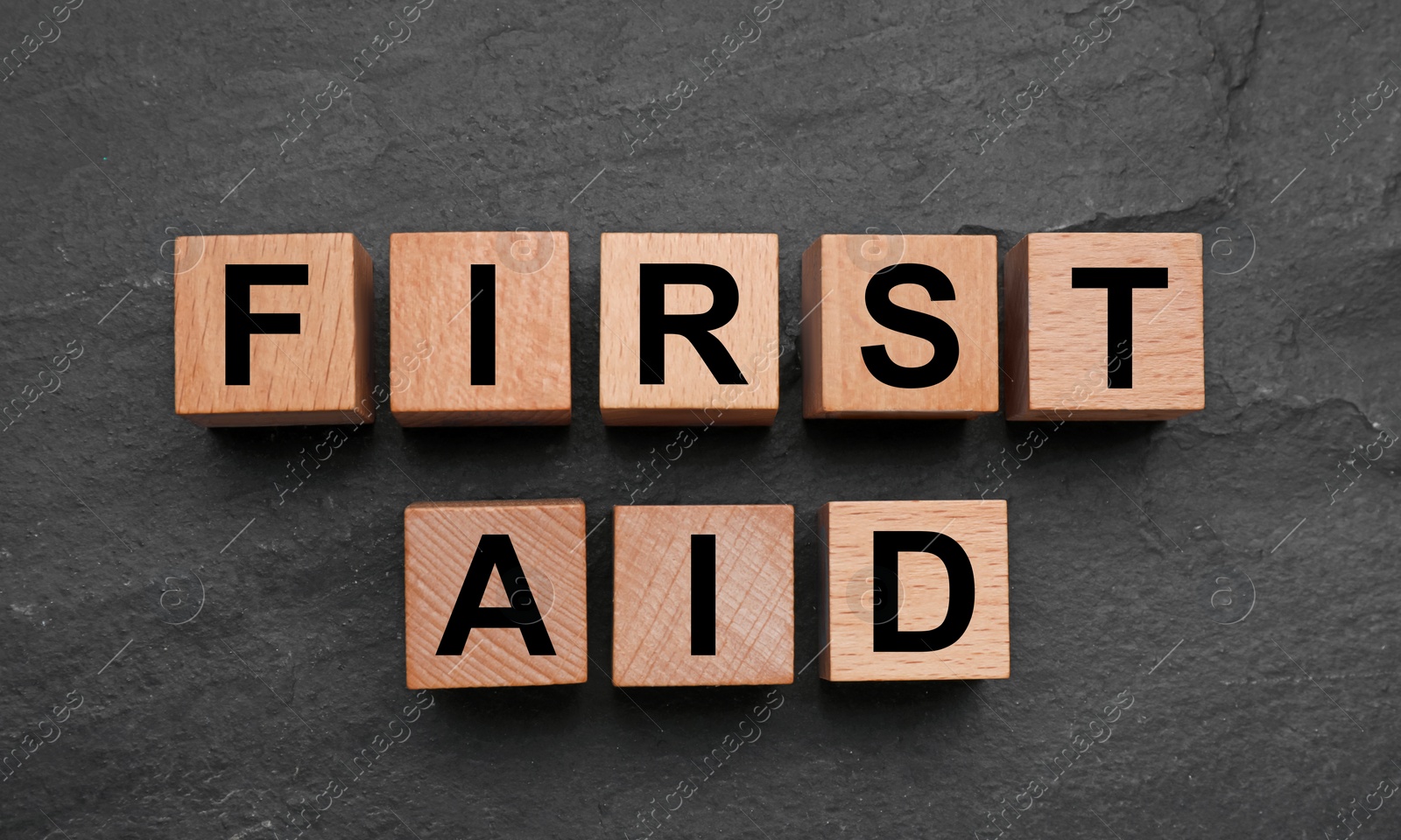 Photo of Words First Aid made of wooden cubes on black table, flat lay